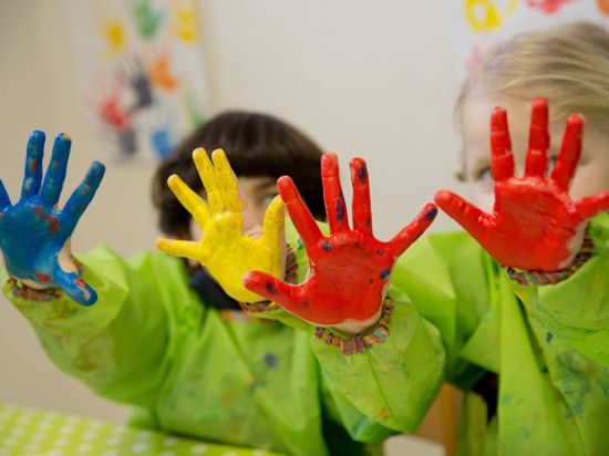 ARCHIV - Zwei Kinder spielen am 19.02.2015 mit Fingerfarben im Atelier eines Kindergarten in Würzburg (Bayern). Wegen nicht bezahlter Kindergartengebühren haben bayerische Kommunen Ausfälle in Millionenhöhe.