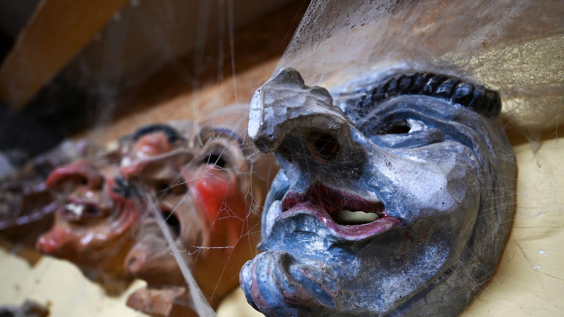 Mehrere hölzerne Narrenmasken hängen in der Werkstatt von Masken- und Holzschnitzer Jogi Weiß