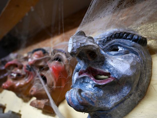 Mehrere hölzerne Narrenmasken hängen in der Werkstatt von Masken- und Holzschnitzer Jogi Weiß