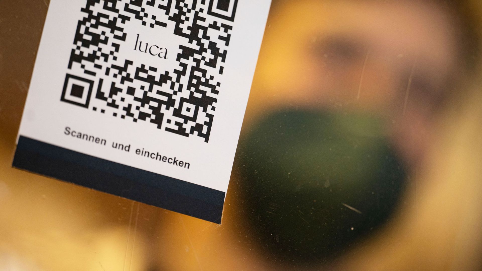 Ein Barcode, der mit der Luca-App gescannt werden kann, wird in die Kamera gehalten.