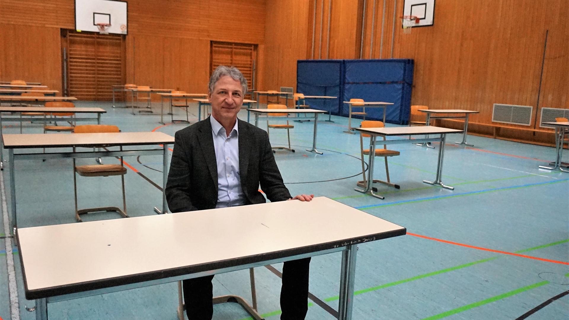 Probesitzen: Markus Braun, Direktor des Ludwig-Wilhelm-Gymnasiums in Rastatt, testet Tisch und Stühle in der Turnhalle. Ab kommendem Montag schreiben dort seine Schüler ihre Abschlussprüfungen.