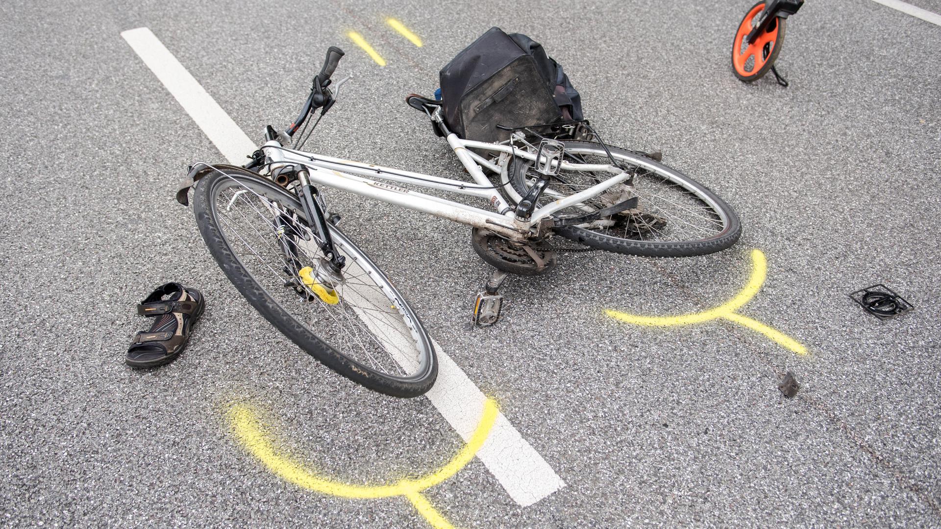 Ein Fahrrad liegt seitlich auf einer Straße, außenrum sind gelbe Markierungen zu sehen.