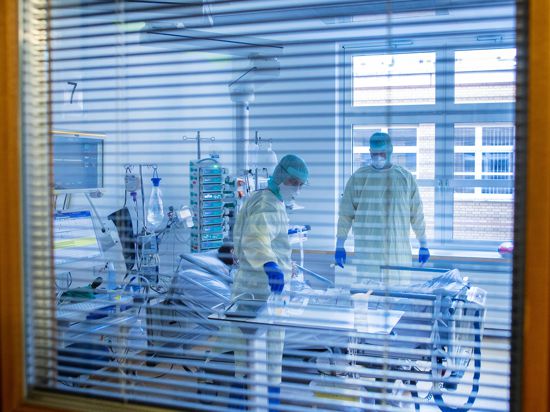 Mediziner und Pfleger versorgen einen an Covid-19 erkrankten Patienten in einem Zimmer des besonders geschützten Teils der Intensivstation des Universitätsklinikums Greifswald. (zu dpa "Engpass bei Intensivbetten droht - Verlegung von Patienten") +++ dpa-Bildfunk +++