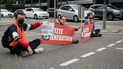 Drei Klimaaktivisten der Gruppe «Aufstand der letzten Generation» blockieren eine Straße in Stuttgart. Die Gruppe «Aufstand der letzten Generation» blockiert seit Monaten deutschlandweit immer wieder Straßen und Autobahnen. Sie fordert ein Gesetz gegen Lebensmittelverschwendung und eine Agrarwende, um Treibhausgase zu mindern. +++ dpa-Bildfunk +++