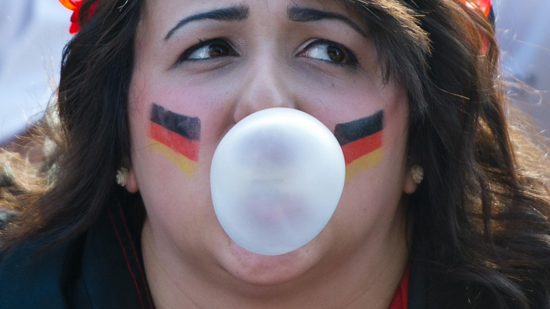 Beruhigt die Nerven: Eine Frau pustet während eines Fußballspiels der deutschen Mannschaft eine Kaugummi-Blase.  