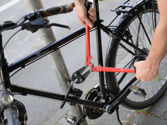 Ein Mann versucht mit einem Bolzenschneider ein Fahrradschloss aufzubrechen.
