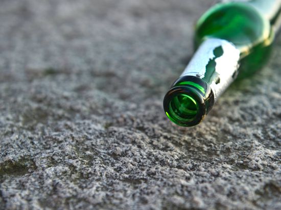 Eine Bierflasche liegt auf einer Steinbank. 