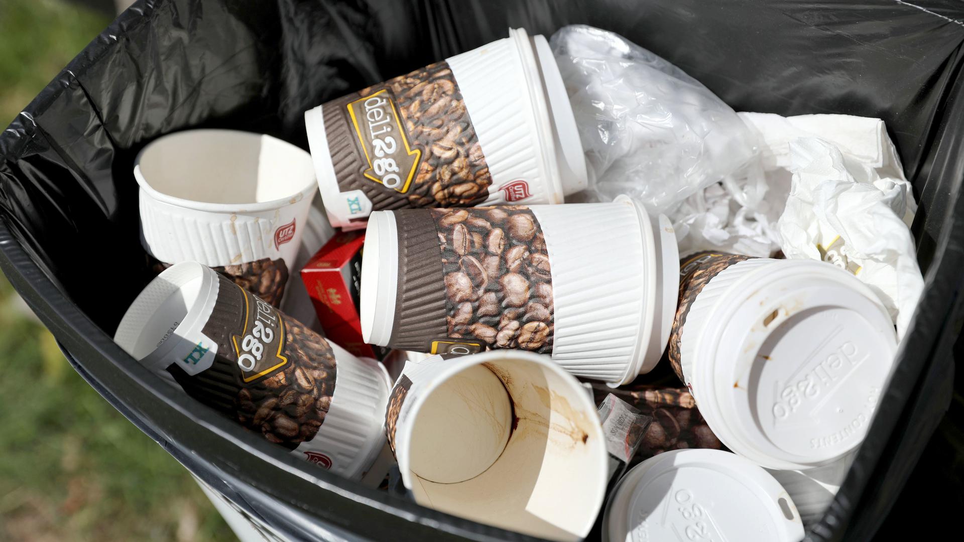 Benutzte Einweg-Kaffeebecher liegen in einem Papierkorb