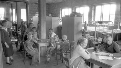 Durchgangslager für Sowjetzonenflüchtlinge in der Appenmühle. Blick in einen Gemeinschaftssaal. Tische, im Hintergrund doppelstöckige Betten und Schränke.
