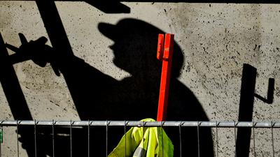 Ein Arbeiter ist auf einer Baustelle beschäftigt und wirft dabei einen dunklen Schatten.