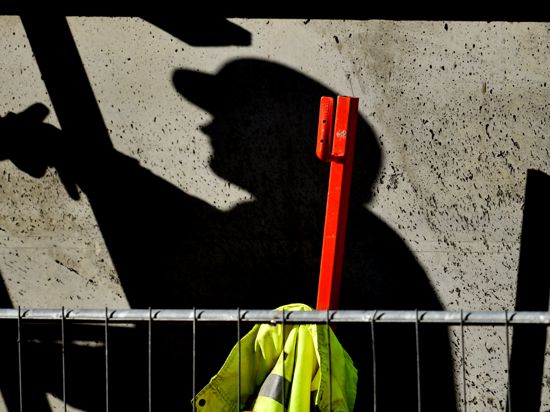 Ein Arbeiter ist auf einer Baustelle beschäftigt und wirft dabei einen dunklen Schatten.