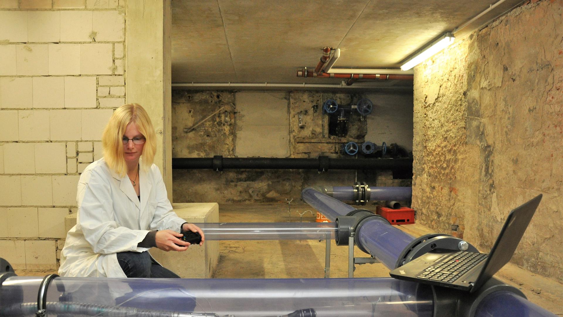 Eine Wissenschaftlerin steuert ein Gerät zur Inspektion von Wasserleitungen in einer Versuchsanlage in Dresden.