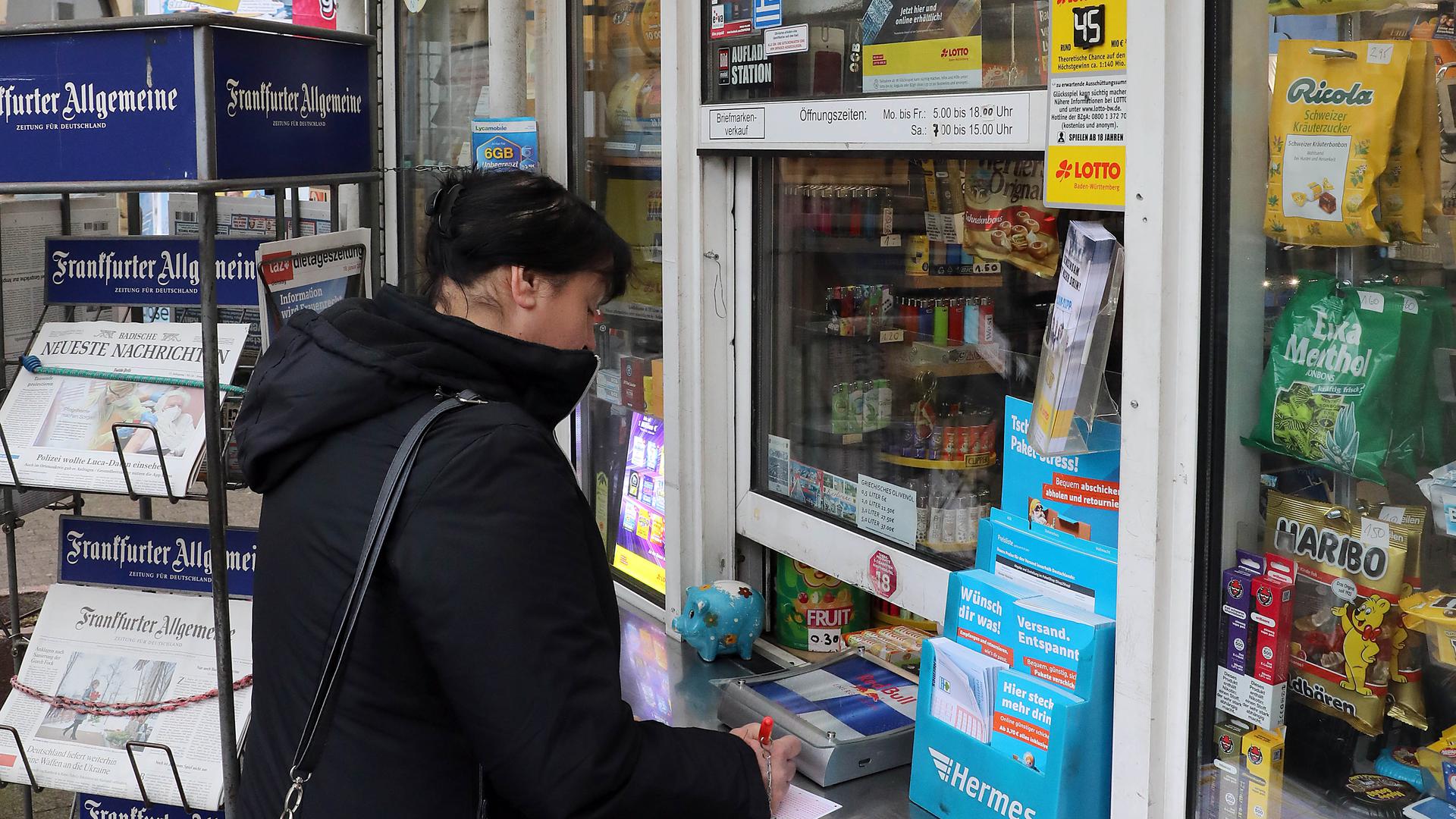 Eine Frau füllt einen Lottoschein bei einem Kiosk in der Karlsruher Oststadt aus.