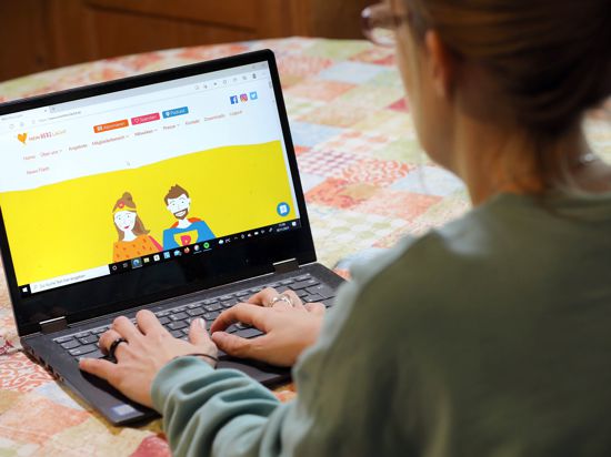 Eine Frau sitzt vor einem aufgeklappten Laptop. Die Internetseite des Vereins „Mein Herz lacht“ wird angezeigt.
