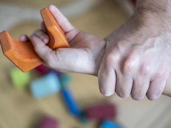 Eine Männerhand umklammert das Handgelenk eines Kindes.