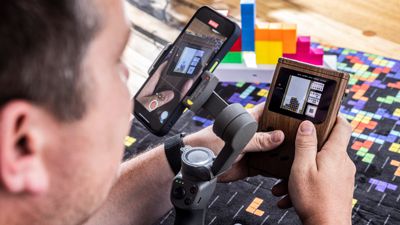 Christian Haupt hält einen Gameboy mit dem Spiel Tetris in der Hand und filmt alles mit einem Smartphone ab.
