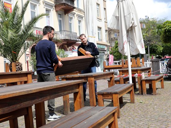Zwei Männer bereiten Tische auf dem Ludwigsplatz vor.