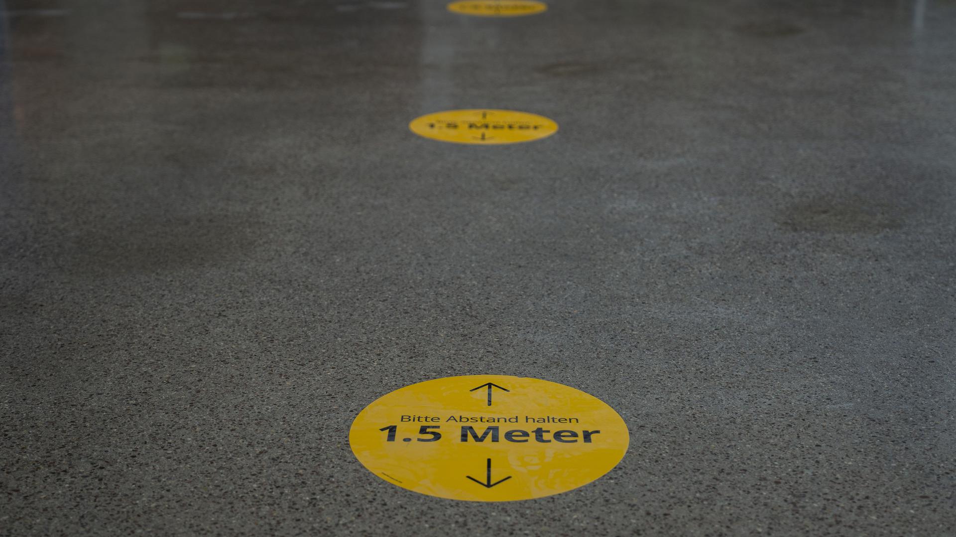 Aufkleber am Boden zeigen den Besuchern die Abstandsregel an.