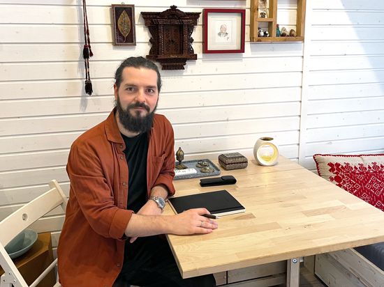 Autor Flavius Ardelean-Bachmann mit Notizbuch und Füller an einem Tisch in seinem Tiny House.
