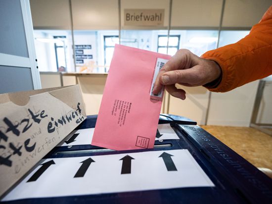Ein Briefwähler steckt im Rathaus Stuttgart seinen Wahlbrief in eine Wahlurne. 