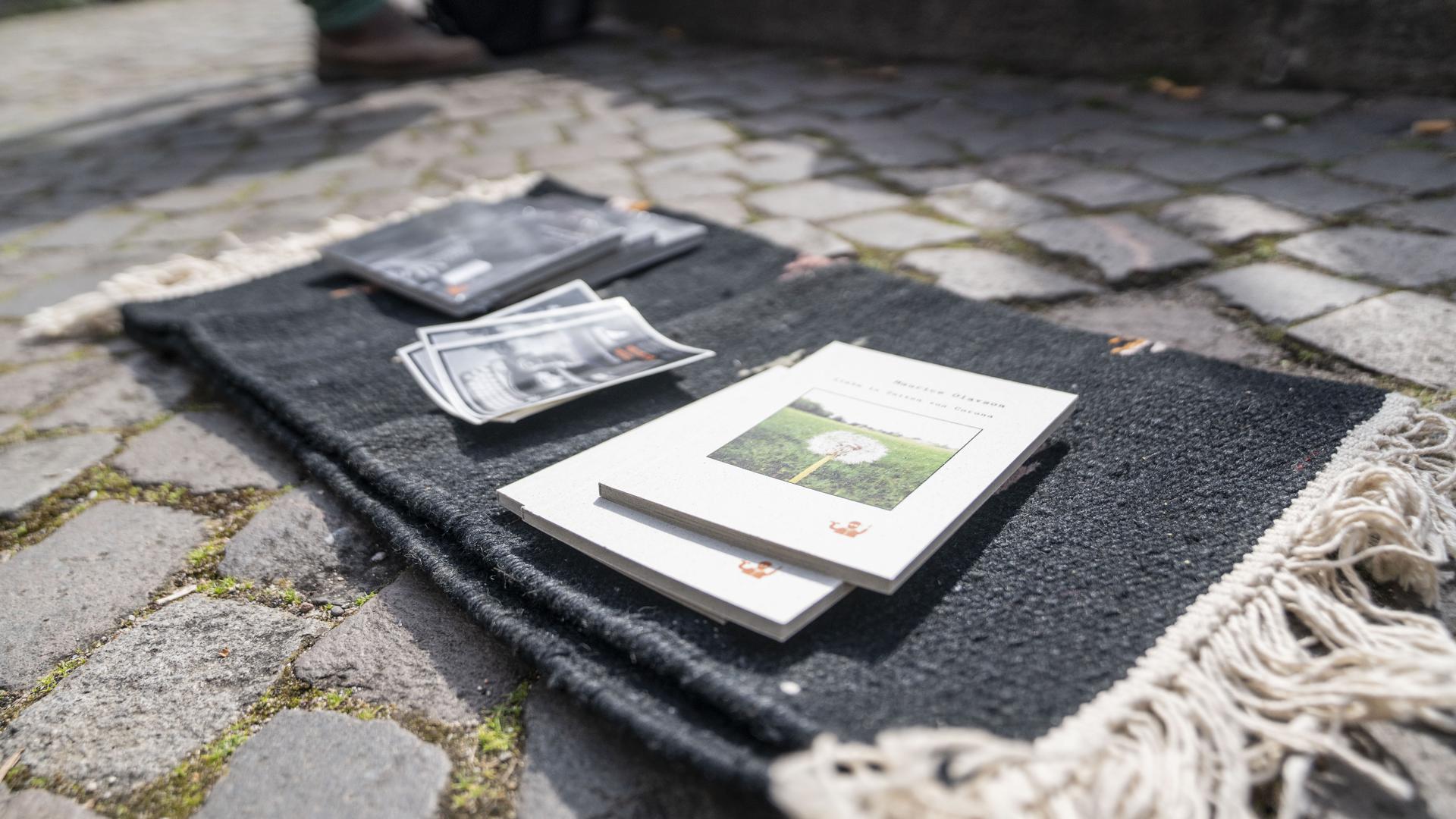 Auf einem Teppich legt der Straßenpoet seine Bücher aus.