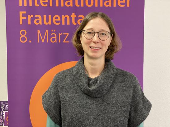 Die Gleichstellungsbeauftragte der Stadt Karlsruhe steht vor einem Banner auf dem „Internationaler Frauentag 8. März“ steht