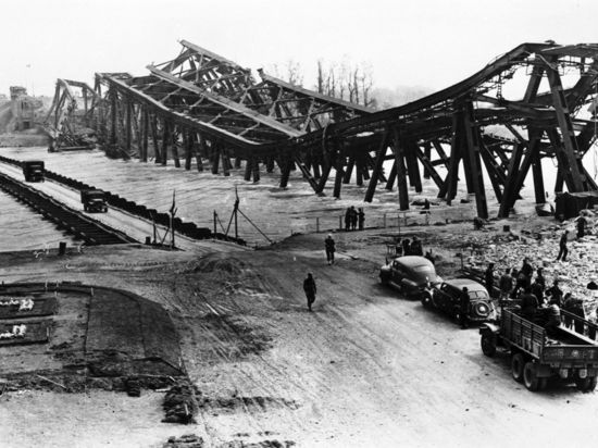 Zerstört und provisorisch ersetzt: Die Rheinbrücke liegt im April 1945 im Wasser. Über die Behelfsbrücke können die Menschen weiter zwischen Karlsruhe und Wörth hin und her fahren.