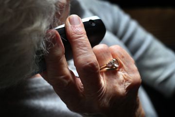 Eine ältere Frau telefoniert mit einem schnurlosen Festnetztelefon