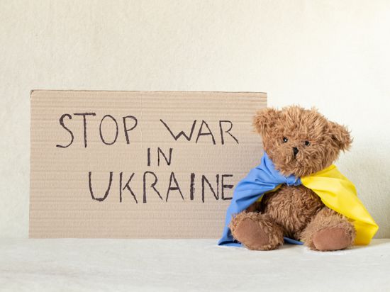 „Stop the war in Ukraine“ steht handgeschrieben auf einem Schild neben einem Teddybär.
