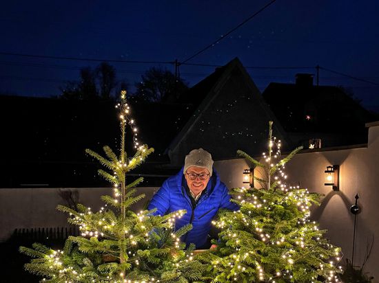 „Weihnachtsbaumguru“ Franz Spitzer mit den zwei beleuchteten Weihnachtsbäumen, die er in Daxlanden aufgestellt hat.