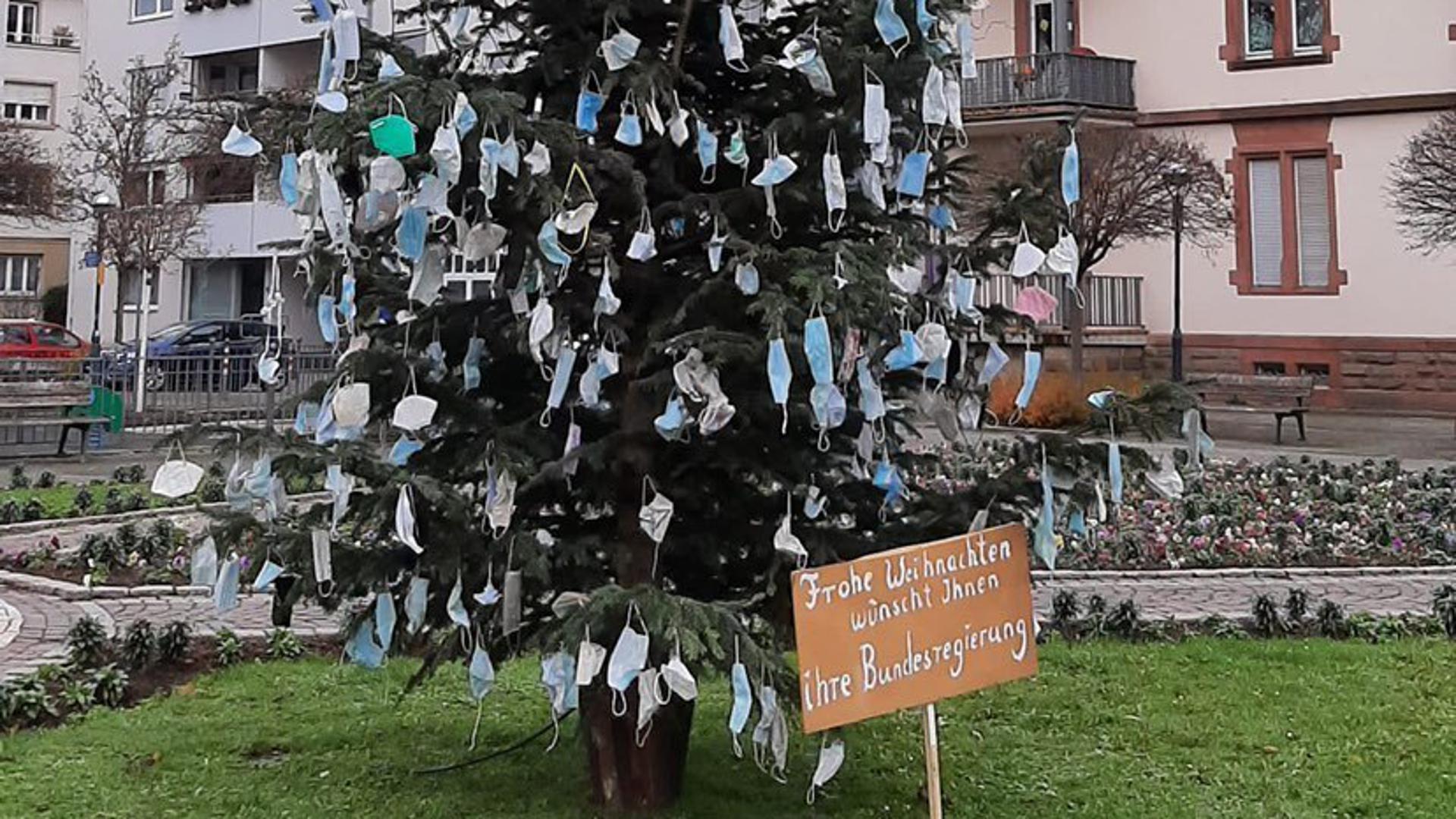 Ein mit Masken behängter Weihnachtsbaum steht auf dem Kolpingplatz.