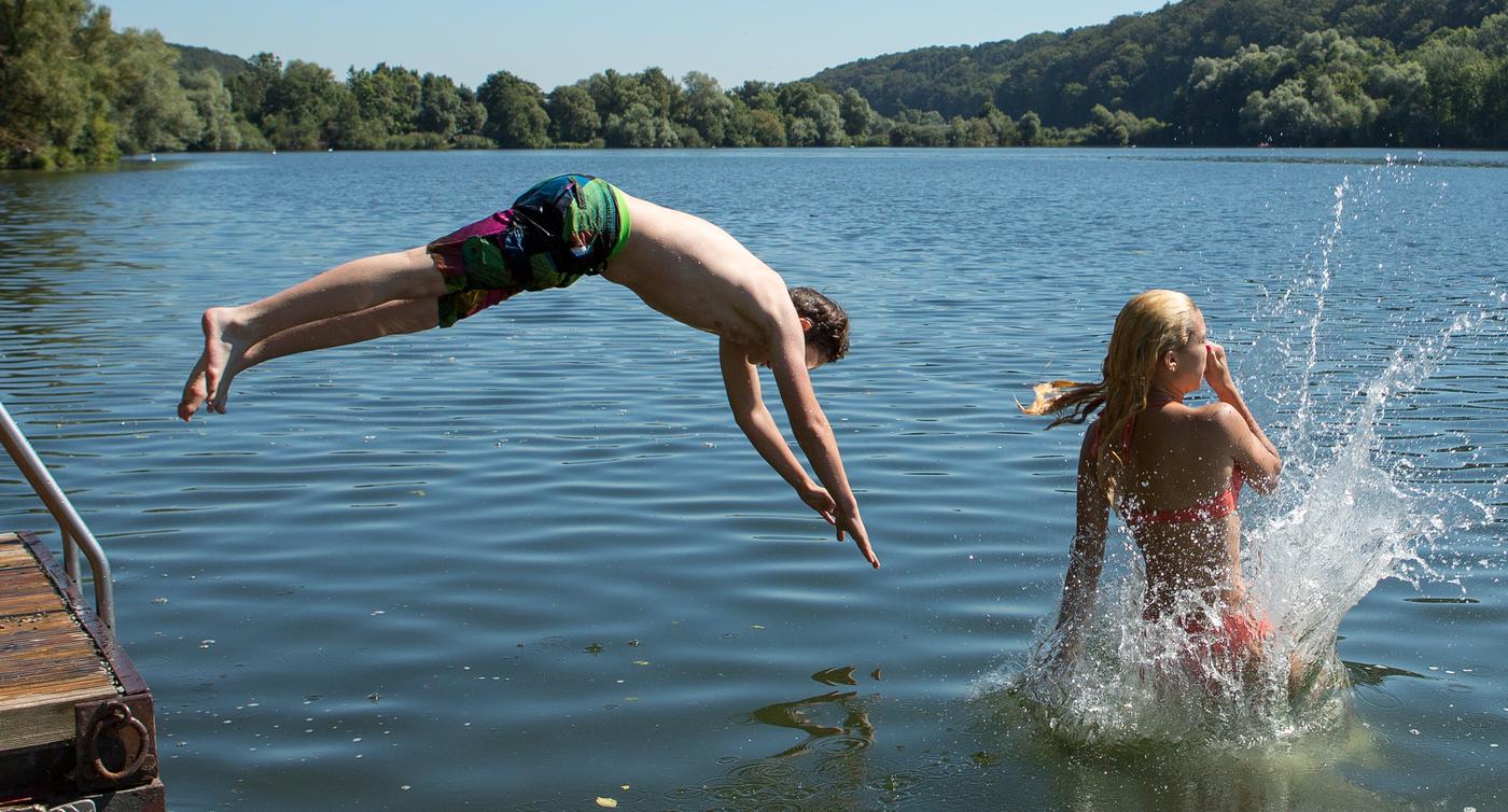 Jugendliche springen in einen Baggersee. 