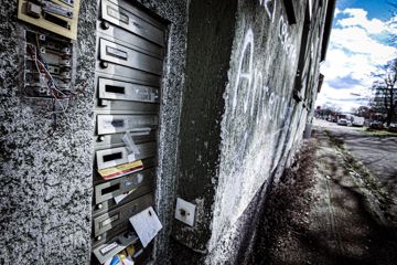 Verwarloste Briefkasten an Hauswand, die mit Graffiti beschmiert ist
