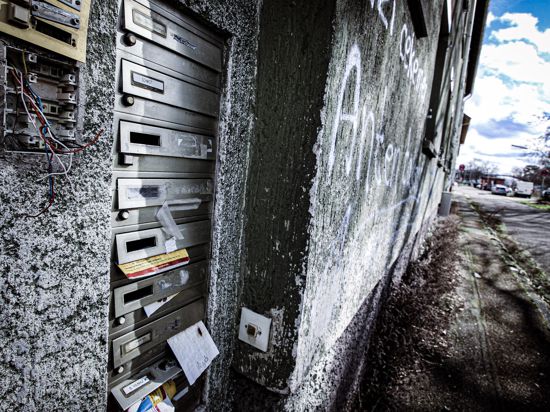 Verwarloste Briefkasten an Hauswand, die mit Graffiti beschmiert ist