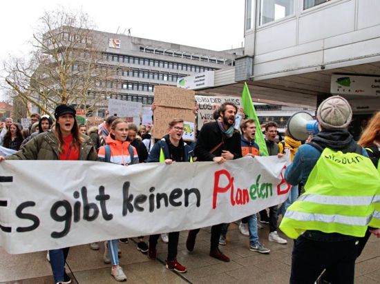 Schüler demonstrieren. Sie halten ein Banner, einer trägt ein Megafon. Im Hintergrund das Pforzheimer Rathaus.