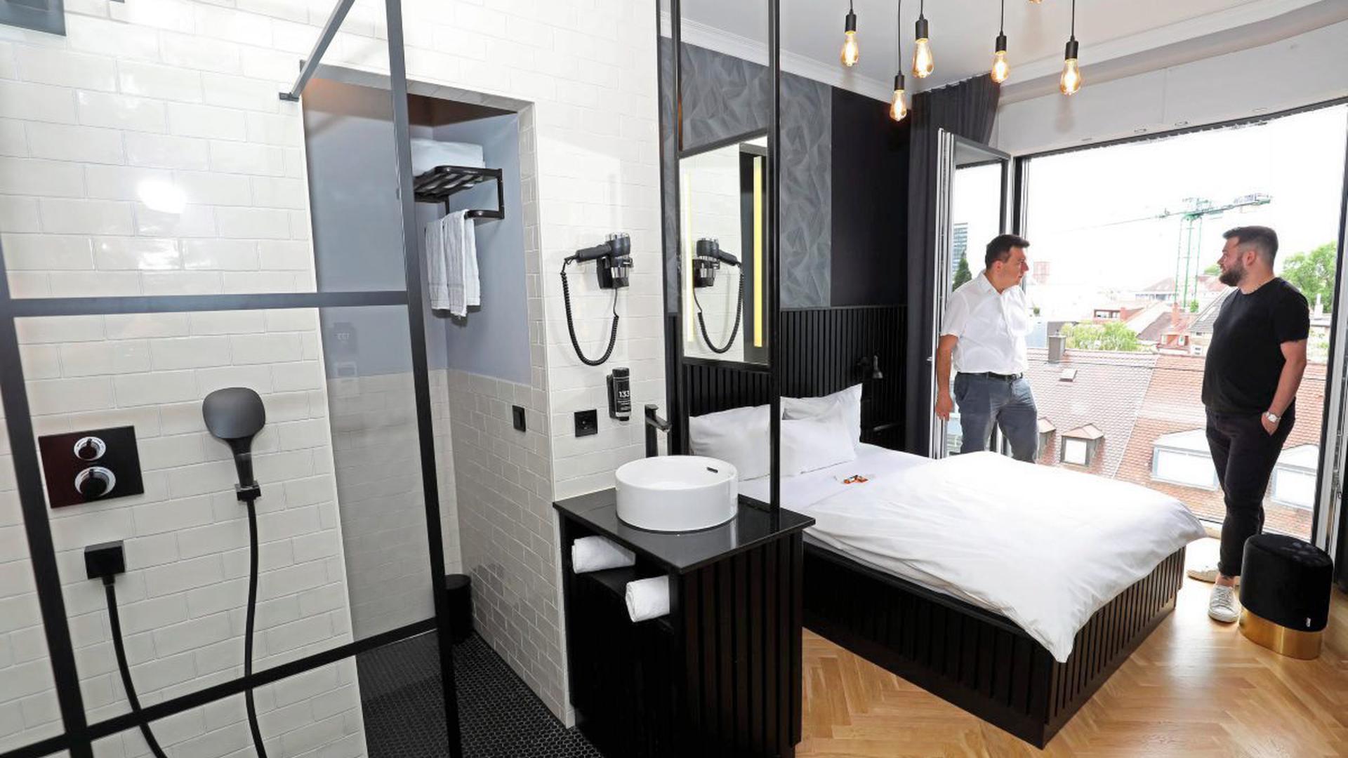 Schwarz-Weiß ist Trumpf: Afrim Bajrami (in Weiß), der Herr der Immobilie, und Steven Ockert, der Betreiber des Boutique Hotels, haben das Zimmer in ihren Farben stylish gestaltet. Dusche und Waschbecken sind im Raum.