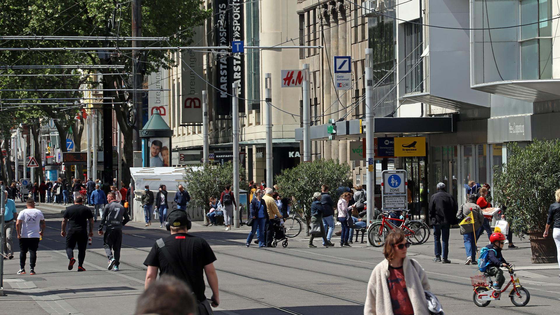 Trotz bestehender Einschränkungen bei Shopping-Erlebnis kehren die Menschen in die Kaiserstraße in Karlsruhe zurück. Beim Bummeln stoßen sie auf Warteschlangen vor Geschäften.