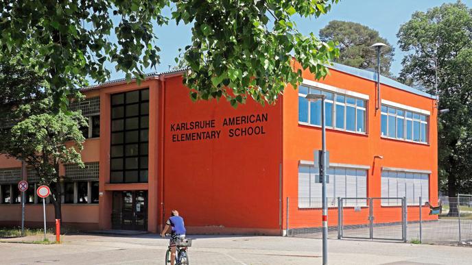 Amerikaner in Karlsruhe: In der Nordstadt weist vieles noch heute auf die Zeit hin, als US-Bürger das Viertel bewohnten. Während die Bekleidung des Radfahrers wohl Zufall ist, trägt die Elementary School ihren Namen aus gutem Grund.