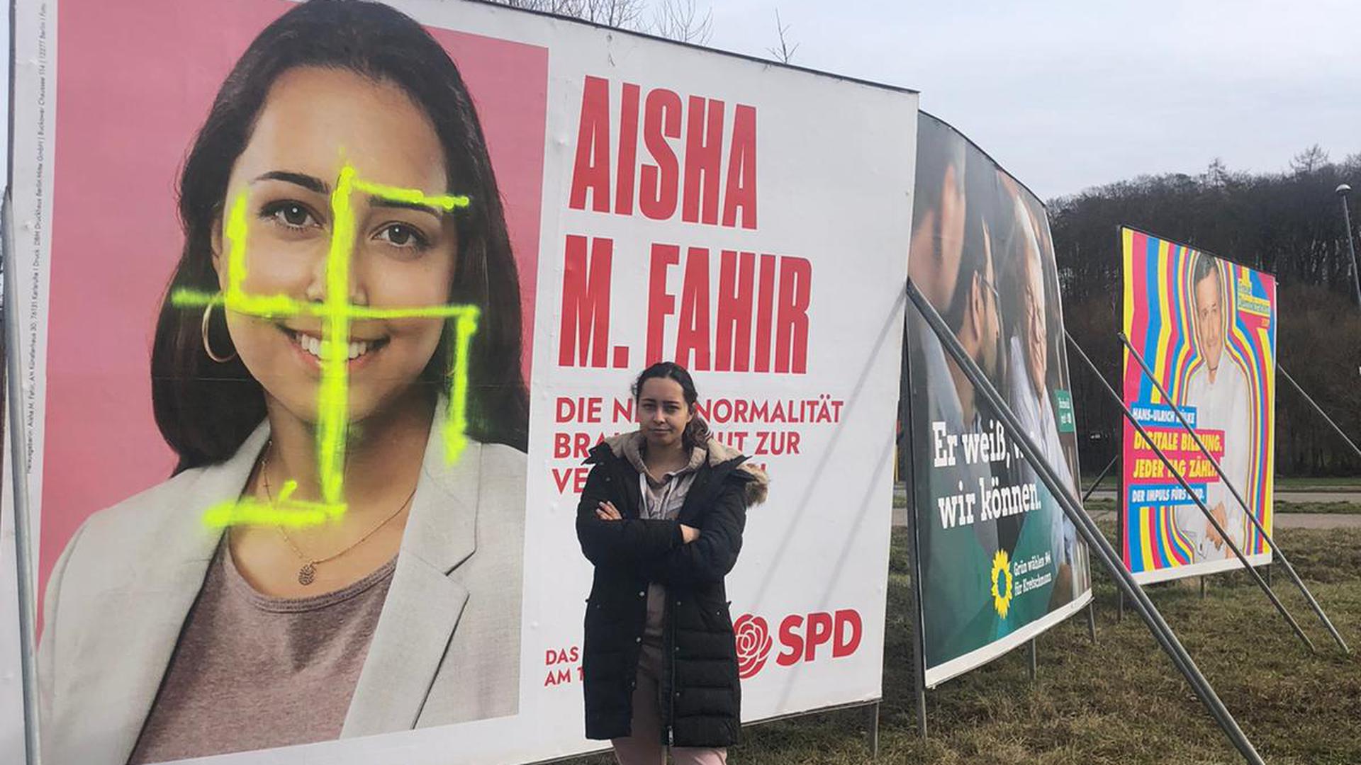 Lässt sich nicht unterkriegen: Aisha M. Fahir, Kandidatin der SPD aus dem Wahlkreis Ettlingen für die Landtagswahl, vor ihrem mit einem Hakenkreuz beschmierten Wahlplakat in Karlsbad.