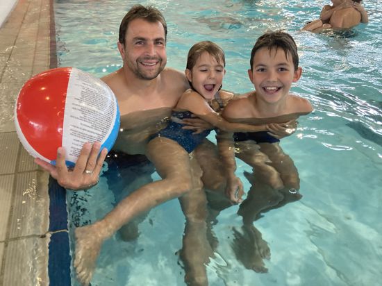 Jens Helfer (links) ist mit seinen Kindern Leon und Lotte im Wasser. Sie haben einen Wasserball dabei.