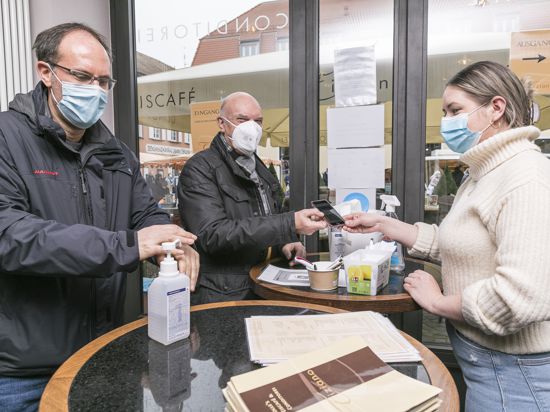 Impfausweis und Händedesinfektion: Michael und Willi Rutschmann (von links) werden am Eingang des Eiscafé Tiziano von Filialleiterin Karina Kandora kontrolliert.