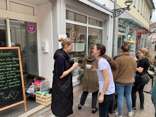 Johanna Löllgen, Inhaberin der Kleinen Kaffeeblüte, stößt vor ihrem Café mit Stammgästen an.
