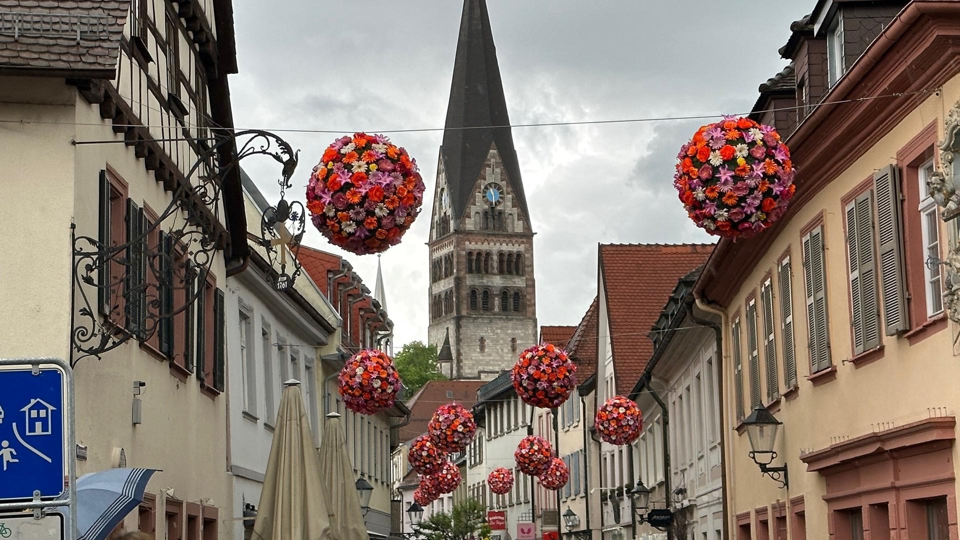 Sommerliches Flair verbreiten die bunten Blumenkugeln, wie sie in der Innenstadt aufgehängt wurden – hier ein Bild aus der Kronenstraße. 