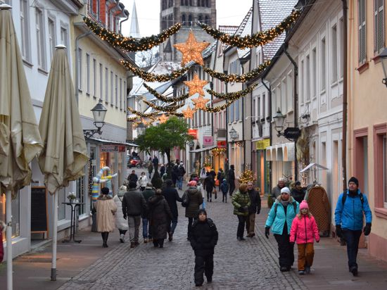 Menschen laufen in der weihnachtlich beleuchteten Ettlinger Kronenstraße.
