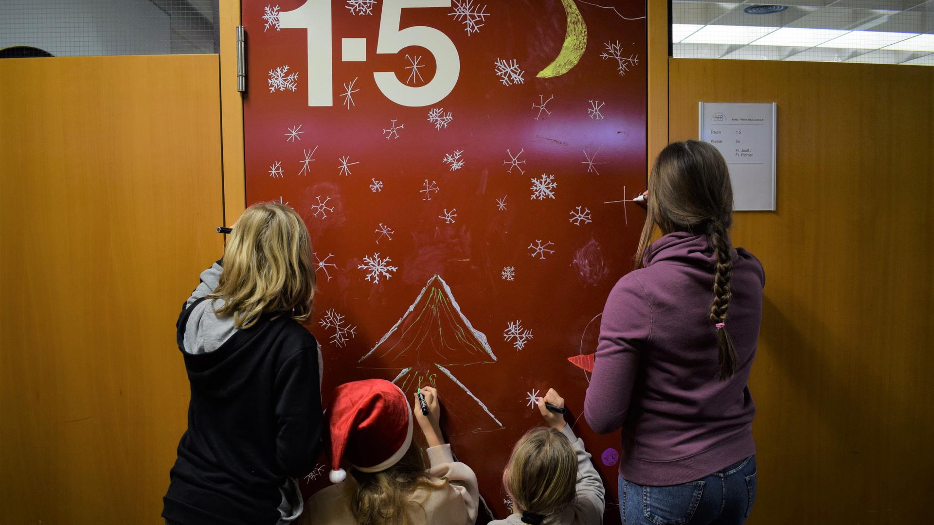 Mit Schneeflocken und einem Tannenbaum bemalen Fünftklässler die Tür ihrer Klassenzimmers in der Anne-Frank-Realschule.