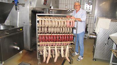 Metzgermeister Jahn Messaros steht mit frischen Würsten in seiner Produktionsstätte