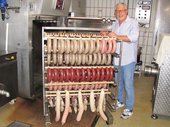 Metzgermeister Jahn Messaros steht mit frischen Würsten in seiner Produktionsstätte