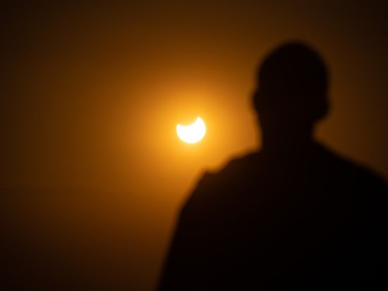 Eine Person beobachtet eine partielle Sonnenfinsternis. +++ dpa-Bildfunk +++