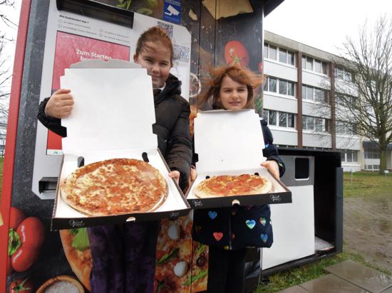 Kleine Pizzafans: Rania (links) und ihre Schwester Lara halten ihre frisch zubereiten Pizzen in den Händen. Papa Sven Hiefer kennt den Automaten im Gewerbegebiet, weil er in der Nähe arbeitet.