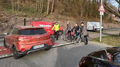 Vier Radfahrer halten auf dem Radweg an der Pforzheimer Straße in Ettlingen, während ein Auto aus einer Ausfahrt auf die Straße fährt.